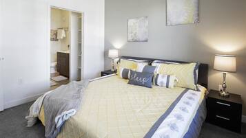 A bedroom with a bed, bedside tables, a nightstand, a wardrobe, and a door leading to a bathroom.