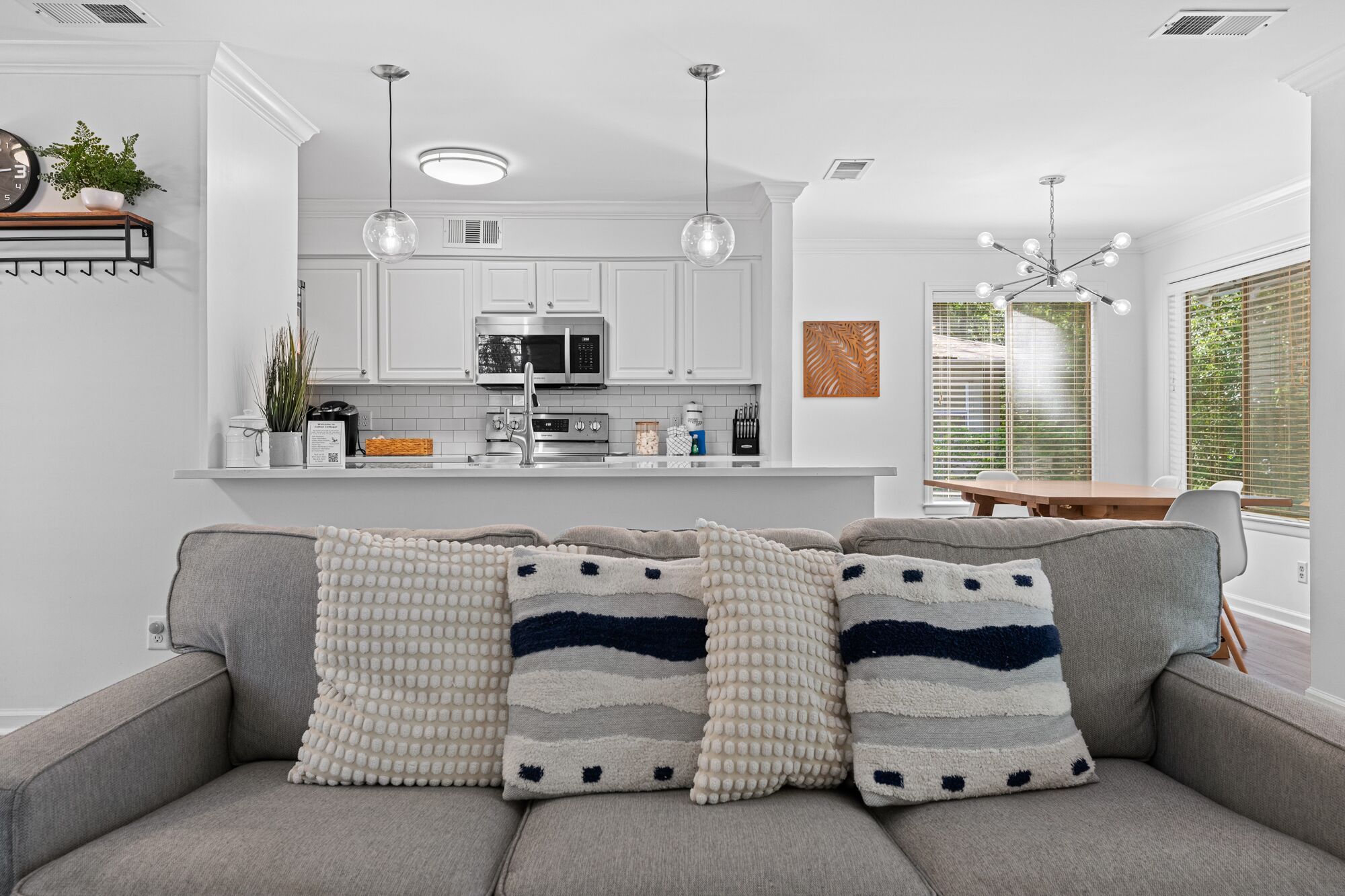 A modern kitchen with white cabinets, stainless steel appliances, and pendant lighting.