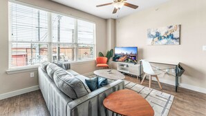 Ein Wohnzimmer mit einer Couch, einem Fernseher und einem Deckenventilator.