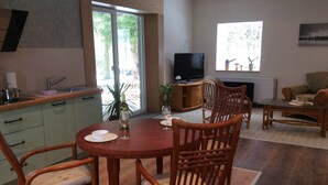 A dining area with a wooden table and chairs, a TV, and a window with a view of trees. - Vacation apartment directly on the lake with private access. (Oberuckersee OT Potzlow)