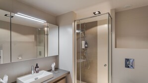 Een moderne badkamer met een douchecabine van glas, een witte wastafel en een grote spiegel.