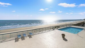 Un espace piscine offrant une vue sur la plage et l’océan.
