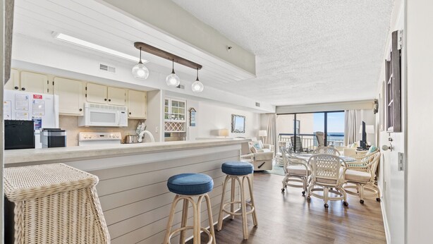 Une cuisine moderne avec un coin bar, des tabourets en bois et une vue sur l’océan.