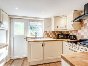 A kitchen with white cabinets, a sink, a stove, and a microwave.