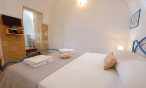Cozy retreat with a neatly made bed, TV, and mirror.