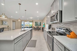 A modern kitchen with a large island, stainless steel appliances, and pendant lighting.