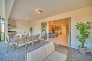 A modern kitchen with a built-in stove, a dining area with a table and chairs, and a large sliding glass door leading to a living area.
