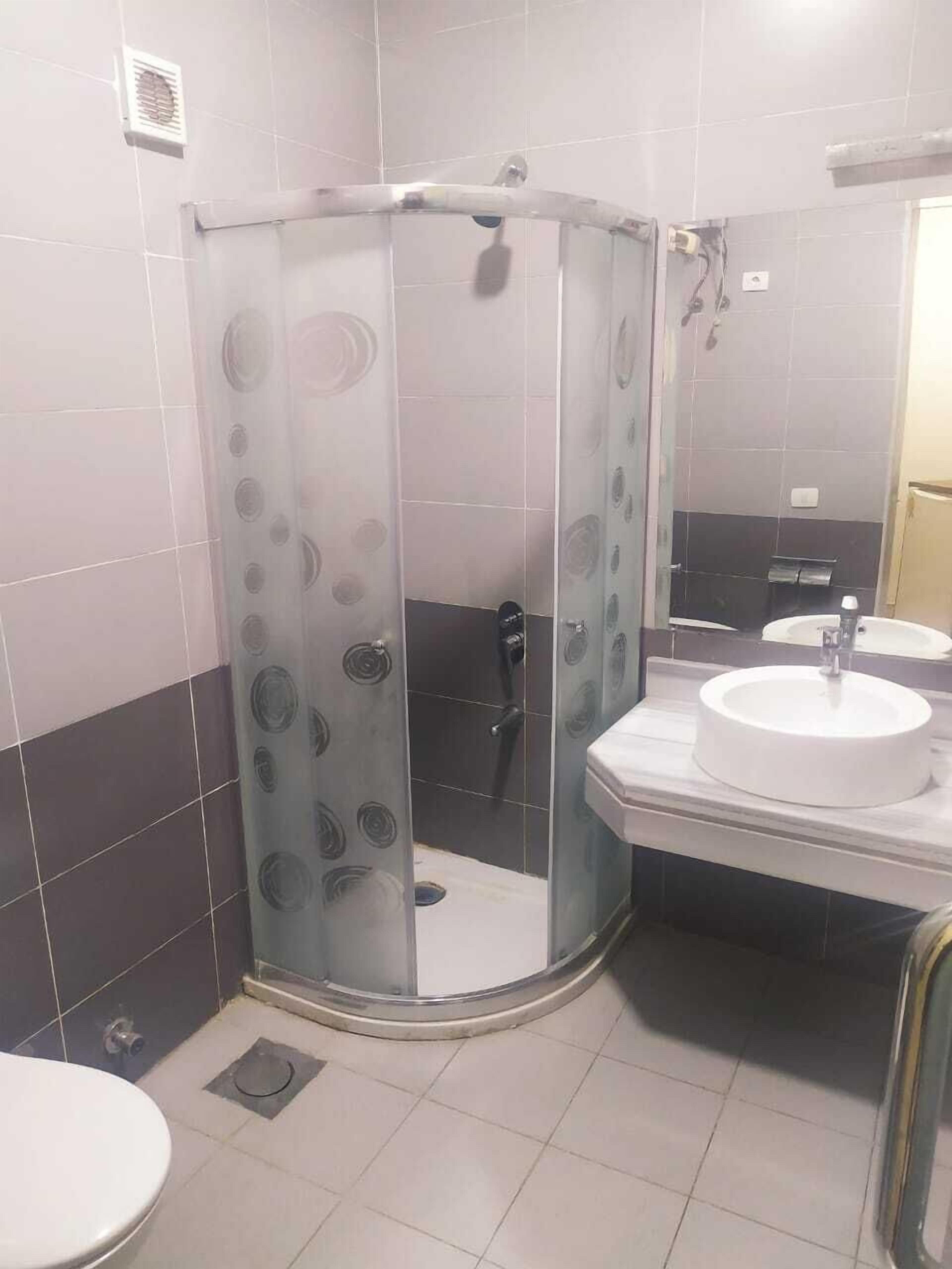 A bathroom with a glass-enclosed shower, a sink, and a toilet.