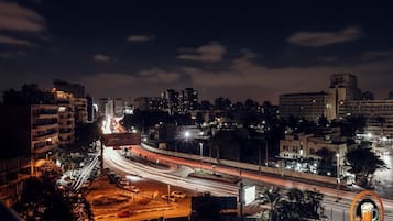 A nighttime cityscape with illuminated buildings and a busy highway.