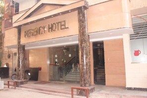 L’extérieur de l’hôtel Regency, avec sa façade en marbre, son comptoir d’accueil et un escalier menant à l’entrée.