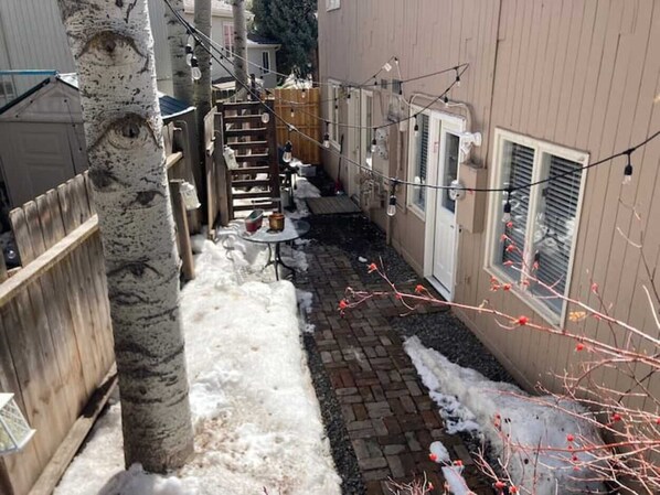 A narrow outdoor pathway with snow on the ground, a wooden fence, and a building with a window and a door. - Mountain modern two-bedroom townhome in West Vail (Vail)
