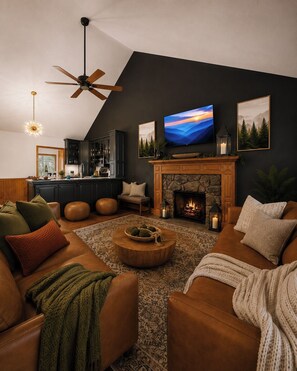Una sala de estar moderna con chimenea, televisor y zona de cocina.