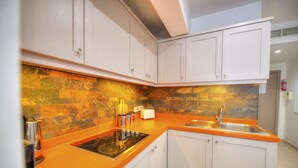 Een moderne keuken met witte kasten, een oranje aanrechtblad, een ingebouwde kookplaat en een spoelbak.