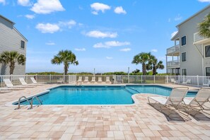 A rectangular swimming pool with a tiled deck, surrounded by white railings and lounge chairs. - Sea Cloisters 103A (North Myrtle Beach)