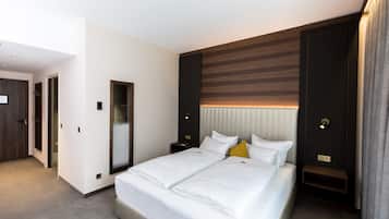 Une chambre d’hôtel moderne dotée d’un grand lit, d’une table de chevet, d’une petite table et d’une tête de lit intégrée.