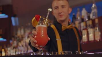 A bartender holding a cocktail with a strawberry garnish.