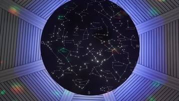A circular star chart with constellations labeled, centered in a room with sloped ceilings and wooden paneling.