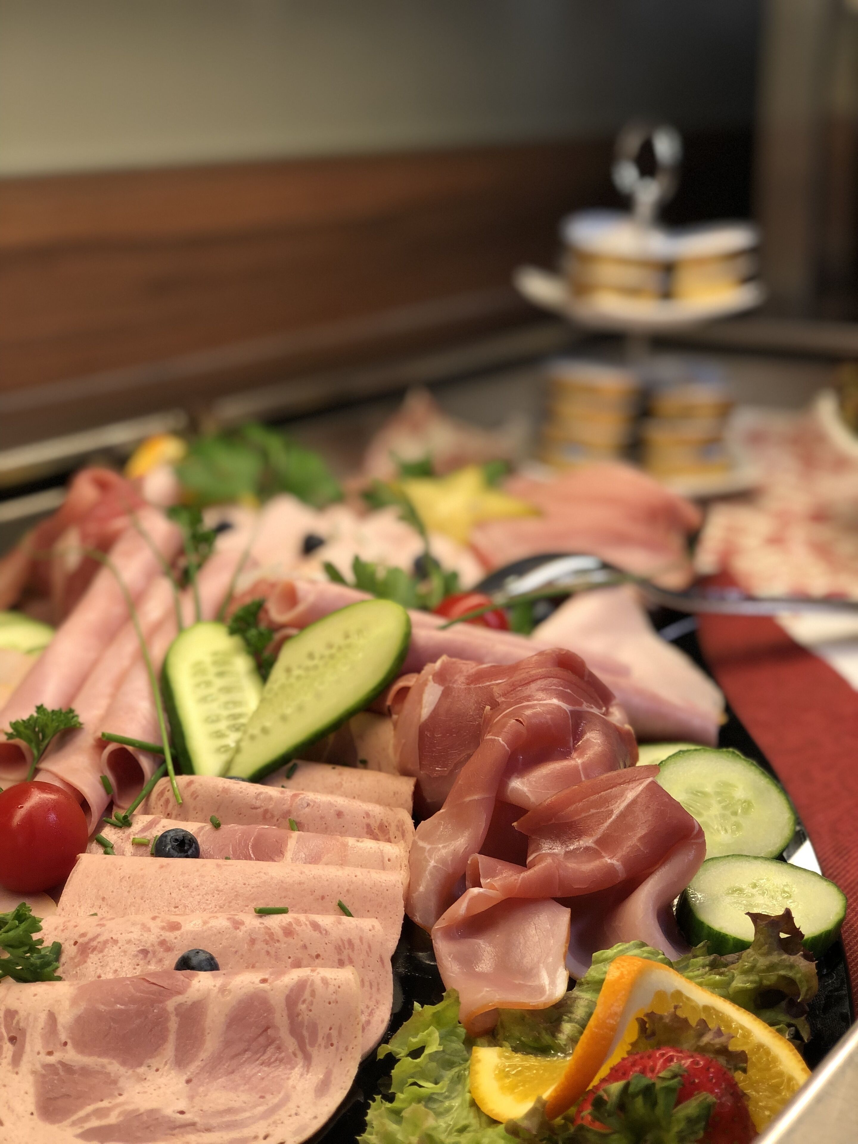 A buffet with various meats, vegetables, and fruits.