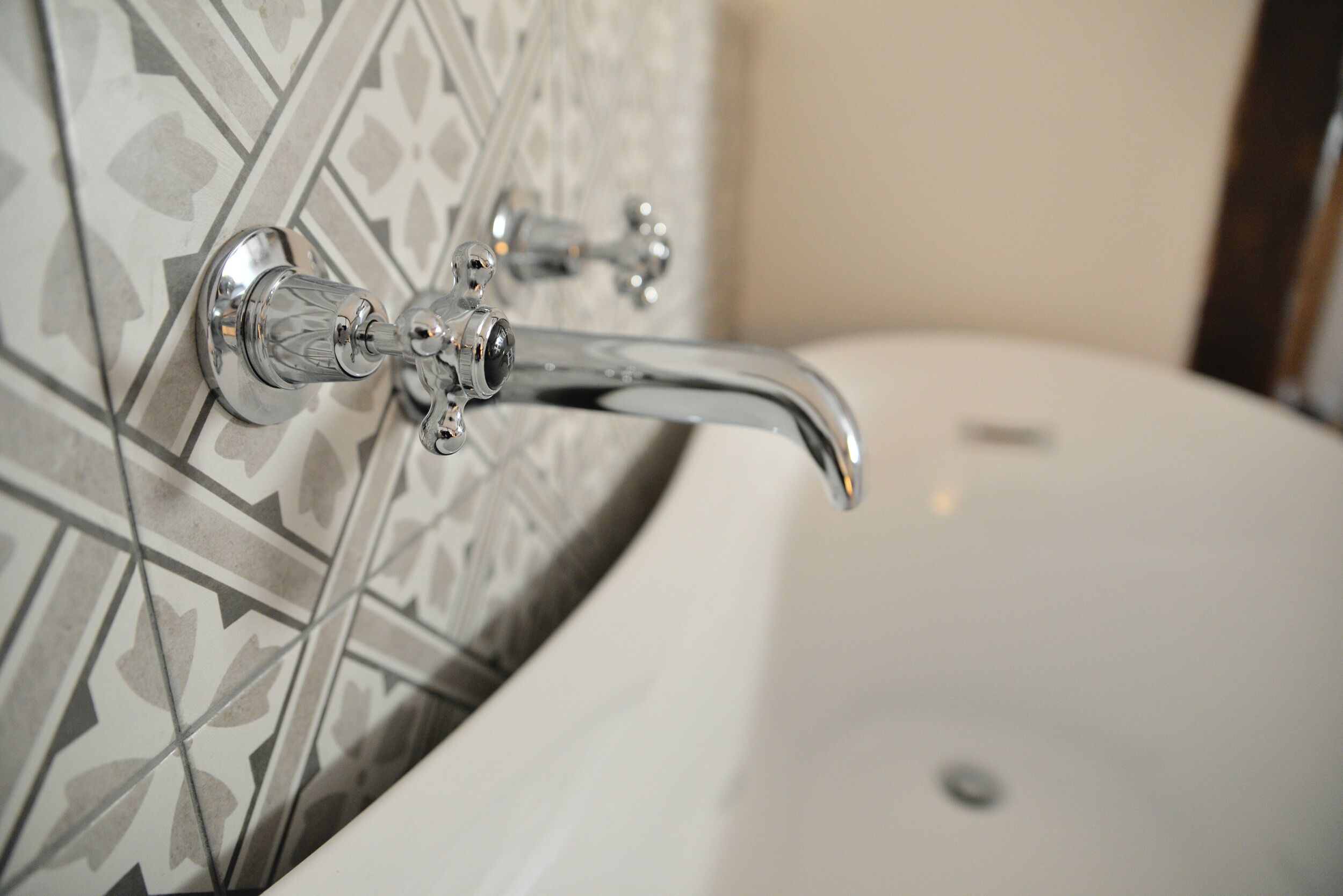 Une salle de bain avec une baignoire blanche, un robinet chromé et des murs recouverts de carreaux à motifs.
