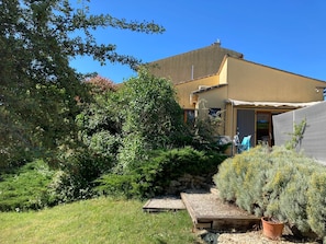 A residential property with a garden, a wooden deck, and a building with a flat roof.