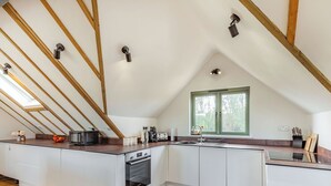 A modern kitchen with white cabinetry, a wooden countertop, and a skylight. - 1 bedroom accommodation in Ongar (Ongar)
