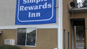 Un edificio con un gran letrero azul que dice 'Simple Rewards Inn'.