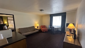 Habitación de hotel con sofá, sillón, mesa de comedor y lámparas.