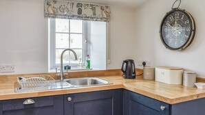 A kitchen with a sink, a kettle, a clock, and a window with a view. - Crogen Gatehouse Lodge (Corwen)