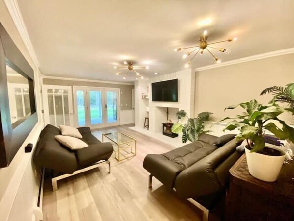 Relax in this stylish living room with a black leather sofa, flat-screen TV, and potted plant.