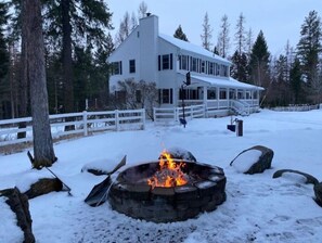 Guests can enjoy a warm fire at the outdoor fire pit surrounded by snow-covered grounds and trees.