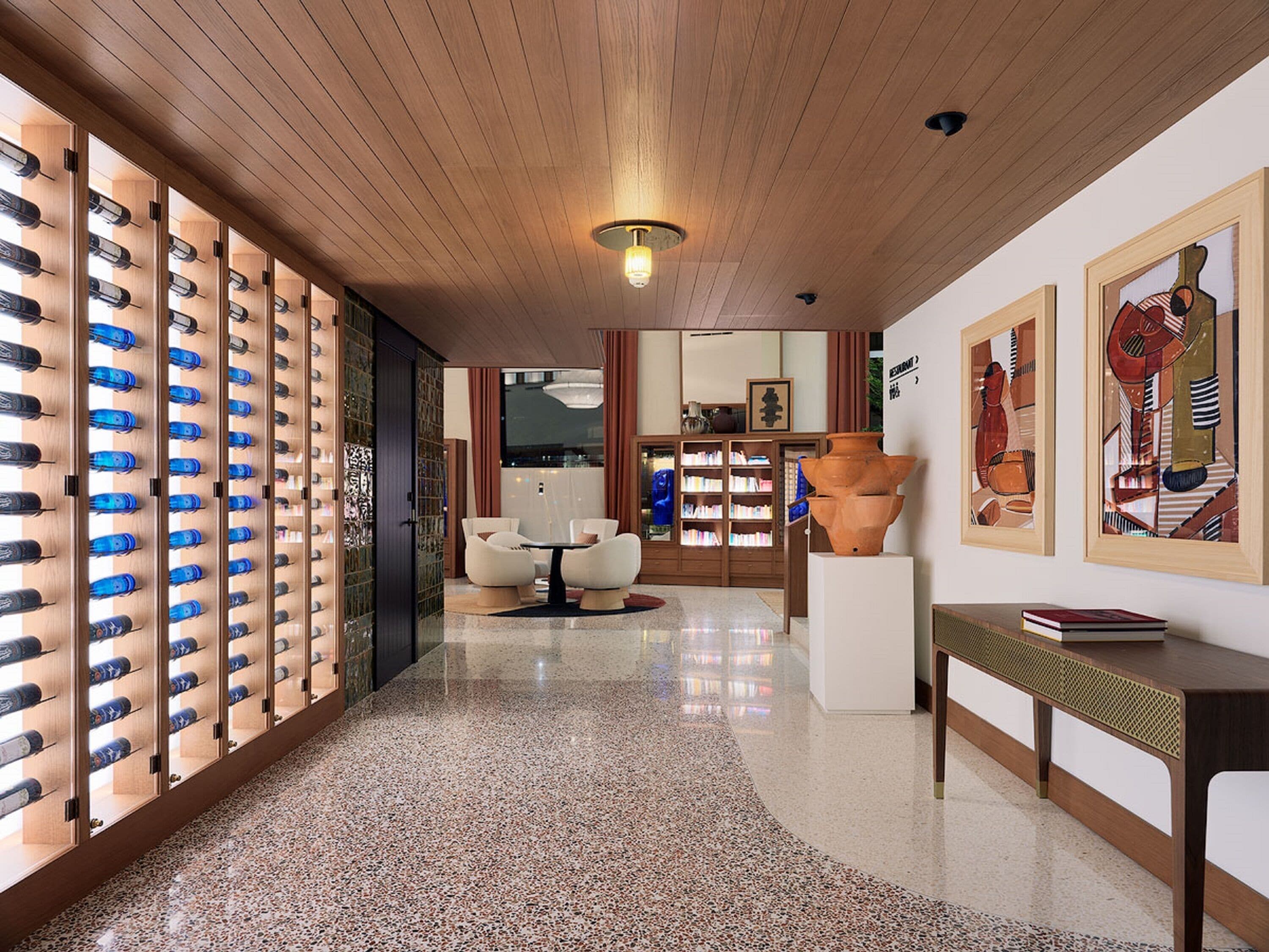 Un moderno vestíbulo de hotel con piso pulido, un área de estar y una exhibición de botellas azules.