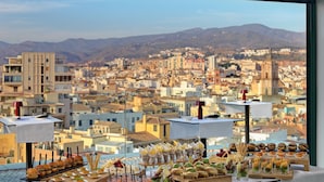 Un espacio para comer en la azotea con vistas a la ciudad, que ofrece una variedad de opciones de comida y bebida.