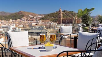 Eine Terrasse mit Tisch für zwei Personen, zwei Biergläsern und einer Schüssel Chips.