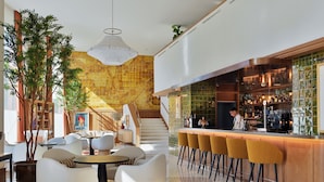 Zona de bar moderna con mostrador, taburetes y una escalera que sube.