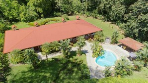 Un resort con piscina, palmeras y un edificio grande de techo rojo.
