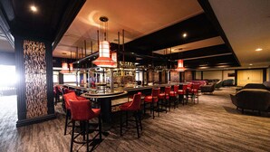 A bar area with red bar stools, a long counter, and hanging red pendant lights. - Appartment Waldidyll Landseite 713 (Timmendorfer Strand)