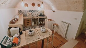 A cozy kitchen with a rustic ceiling, a tiled backsplash, and a dining table set with a placemat and a polka-dotted pot.