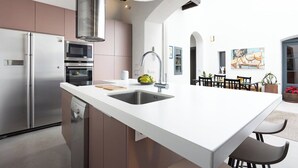 Una cocina moderna con una isla central, electrodomésticos de acero inoxidable y un comedor con mesa y sillas.