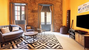 Una sala de estar acogedora con pared de piedra, un sofá, una mesa de centro y un mueble para la televisión.