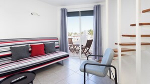 A modern room with a striped sofa, a chair, a small table, and a sliding glass door leading to an outdoor area. - Home2Book Beach & Nightlife Las Américas, Terrace (Playa de la Américas)