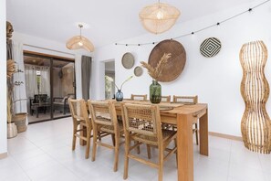 Een eethoek met een houten tafel en stoelen, omringd door wanddecoratie van geweven materiaal en lichtjes.