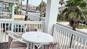A covered outdoor seating area with a round table and striped cushioned chairs.
