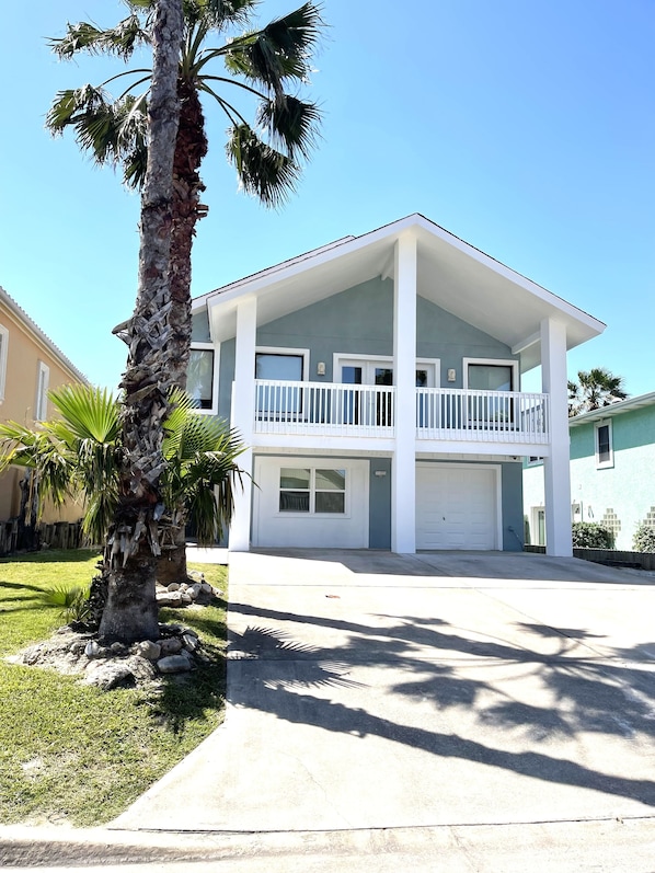 A two-story residential building with a balcony, a garage, and a well-maintained lawn.