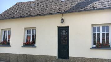 A building with a tiled roof, a black door, and windows with flower boxes.