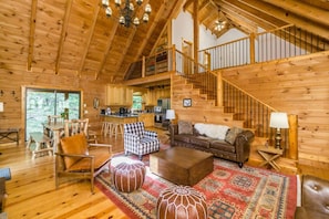 A spacious wooden cabin with a large living area, a kitchen, and a staircase leading to an upper level.