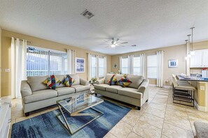 A living room with two sofas, a glass coffee table, and a dining area with a kitchen counter. - 576 - Stunning Modern Resort Home With Private Pool And Spa (Davenport)