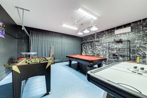 A room with a foosball table, pool table, and a billiards table. - 576 - Stunning Modern Resort Home With Private Pool And Spa (Davenport)