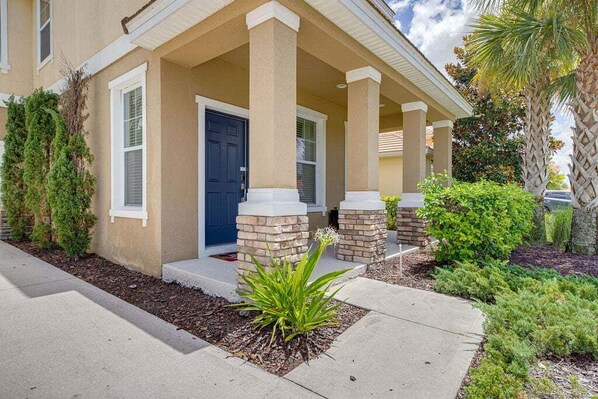 A two-story house with a front porch, a blue door, and a small garden area. - 576 - Stunning Modern Resort Home With Private Pool And Spa (Davenport)