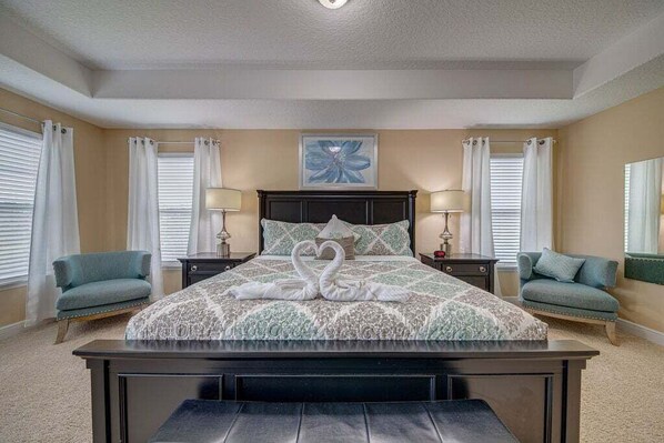 A bedroom with a bed, two nightstands, two lamps, a wall art piece, and two chairs. - 576 - Stunning Modern Resort Home With Private Pool And Spa (Davenport)