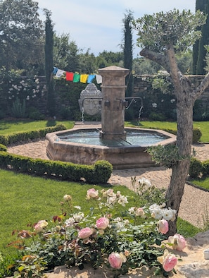 A garden with a fountain, roses, and a Buddha statue.